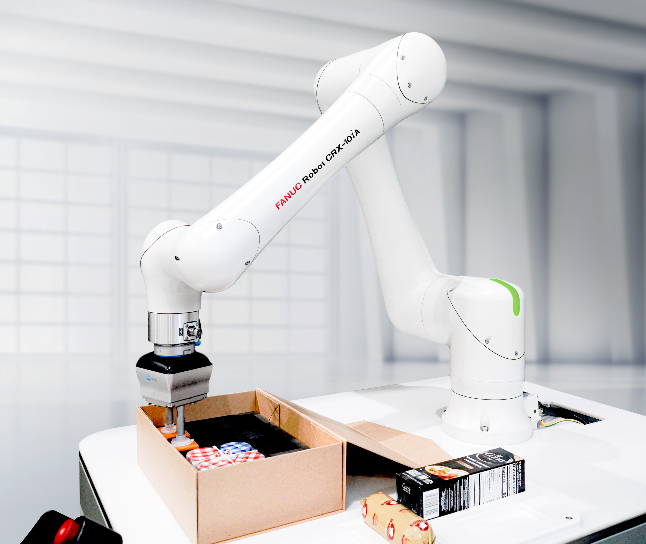 FANUC's CRX-10iA food grade variant picking and packing an assortment of food items.